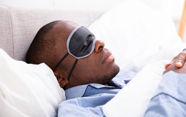 A man with insomnia sleeping with a sleep mask